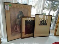 Three framed prints displayed near window: large poodle print with water damage, smaller portrait print with water damage, and signed 'Three Men' print.