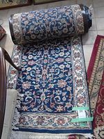 Rolled-out blue floral patterned runner rug with detailed borders and fringed edges