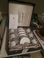 Boxed set displaying six demi-tasse cups and six matching saucers arranged in satin-lined display box.