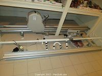 View of the full stairlift rails and motor unit laid out on the floor, showing the aluminum rail sections and motor housing.