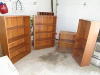 Four faux wood bookcases arranged in a garage, showing full set and size difference.