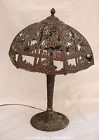 Full view of the antique Miller era table lamp showing the whole lamp with bronze-finished reticulated metal shade and base.