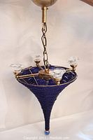 Full view of cobalt glass beaded chandelier hanging, showing conical shape and four brass light holders with clear glass shades
