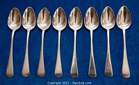 Eight sterling silver spoons arranged in a row on a blue fabric background, showing size and shape.