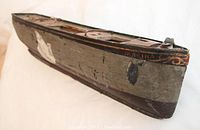 Full view of the handcrafted wooden and metal sailboat showing its aged painted surface and folk art bird design on the side.