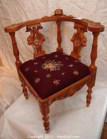 Full front view of corner chair showing overall shape, upholstery and carving.