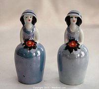 Front view of both porcelain lady salt and pepper shakers showing blue dresses with lustre finish, floral bouquets, and hats