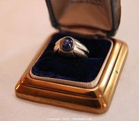 White gold ring with a star sapphire in an old ring box with blue velvet interior and gold edges.