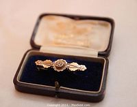 Front angle of the antique 15k gold brooch in its box, showing detailed design and blue velvet lining