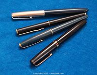 Four vintage Parker fountain pens arranged on blue background showing barrel and caps, various colors with gold clips and trim.