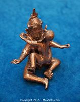 Photo of erotic metal couple sculpture showing female figure seated on male's lap with arms wrapped around him, detailed headdresses and jewelry visible.