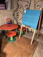 Photo showing the chalkboard next to orange pumpkin-themed table with two matching stools in basement setting