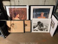 Six framed art prints arranged on floor by wall, including infant and glamour prints
