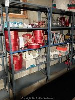 Two tall metal shelving units in a garage setting. Shelves hold various items but contents are excluded from sale.
