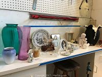 Wide view of shelf showing all vases, decorative plates, figurines, and other small decor items arranged.