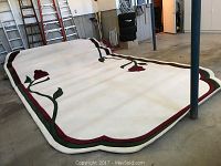 Image showing the full rug laid out with visible rose pattern and scalloped colored border, minor wear apparent on surface.