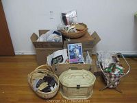 Overall view of three main piles of sewing items including baskets, boxes, and clothes shaver package