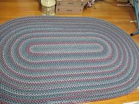 Top-down view of oval braided rug showing full pattern and condition on hardwood floor.
