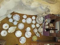 Overview of all china items displayed on floor and table, showing multiple sets of cups, saucers, bowls, candy dish and tea pot items.