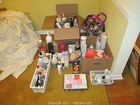 Photo showing multiple boxes and baskets containing personal care items including lotions, sprays, soaps, and hair treatments placed on carpeted floor.