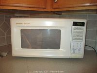 Full side view of Sharp Carousel microwave placed on kitchen counter, showing the door and keypad panel.