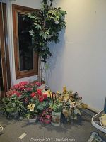 Photo showing 7 ft faux tree with green leaves near window and multiple potted artificial flower arrangements on the floor.