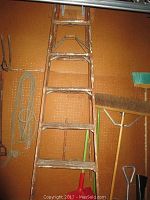 Wooden ladder approximately six feet tall leaning against a wall with ladder showing signs of use and wear.