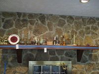 Shelf with various items including oil lamps, brass bell, decorative scale, vase, candle holders, figurines, and bookends