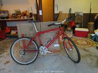 Red Cannondale bicycle in a garage setting showing overall condition and missing tires.