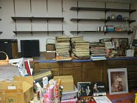 Three tall stacks of LP albums on countertop, two narrow stacks of 45s at right, empty wall shelves above