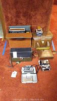 Overall view of collection showing multiple vintage cameras and carrying cases arranged on carpet