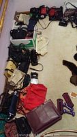 Image showing large assortment of purses spread on floor in multiple colors including red, beige, black and purple dumbbells.