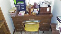 Desk with chair and items including shredder box, percussion instruments, wooden bookends, small office accessories.