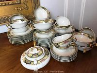Full set of Limoges Elite china arranged showing plates, cups, bowls, and covered dish with floral and gold trim decoration.