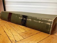 Side front view of the bound volume showing its thickness and green cloth cover with visible wear.