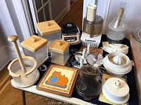Photo showing the Cuisinart CFP9 food processor, multiple plastic attachments, instruction manual, wood kitchen canisters, and paper towel holder on a table