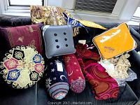 Photo of assorted pillows, fleece blanket in bag, fringed fabric, and curtains in background