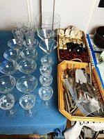 Photo of crystal wineglasses, goblets, and clear glass truffle bowl on blue cloth-covered table.