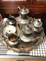 Full view of the tea set on the large ornate silver plated tray showing all pieces including the teapots, creamer, sugar bowls, and covered dish