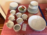 Full view of white Rosenthal china set arranged on table including bowls, plates, mugs, and saucers