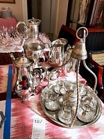 Full view of the silver plate urns, pitcher, creamers, sugar bowl, and Turkish tea set on tray with cups, saucers, spoons, and miniature teapot.