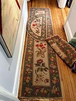 Photo showing the three matching floral rugs laid out in hallway, including runner, half-moon doormat, and area rug with floral designs in beige, green, red, and yellow.