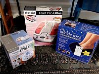 Three boxed products: Homedics Foot Pro Ultra foot massager, Twinkle Toes foot massager, and Homedics Body Basics Enviraspa sound and aroma machine.