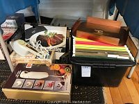 View of kitchen appliances and filing supplies showing hand mixer boxed, vacuum sealer box, steam iron, and crate of files.