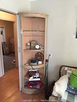 Wood curved corner shelf installed in corner of a room, showing multiple shelves and some items on lower shelves (not included).
