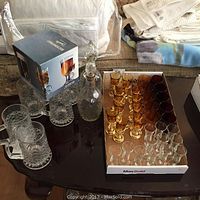 Full view of glassware set, showing beer mugs, boxed coffee glasses, decanters, and amber, cranberry, and clear glasses on table.