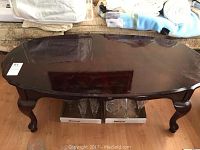 Top view of the dark, glossy, oval-shaped coffee table showing surface wear and some light scratches.