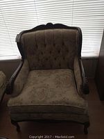 Front view of vintage upholstered accent chair with carved wooden frame and floral tufted upholstery.