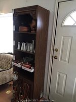 Full view of vintage wood shelving unit showing four shelves and two cabinet doors at bottom, next to a white door and furniture.