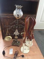 Glass and brass scale lamp with etched floral glass shade, two wooden and metal lamp bases in view.